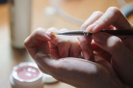 The manicurist applies varnish on the nail close-up. Coating the nail with varnish