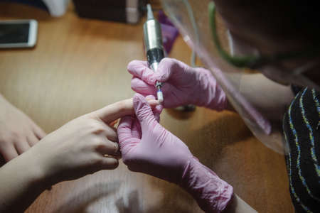 Manicurist makes hardware manicure close-up. Treatment of nails with the help of hardware manicure...