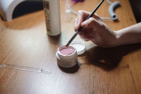 The manicurist applies varnish on the nail close-up. Coating the nail with varnishの写真素材