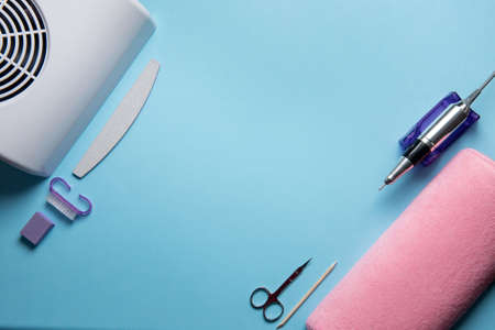 Beauty accessories for manicure and pedicure on a blue background,. Samples of nail polish, scissors, manicure ultraviolet machine, nippers and other accessories for home and salon proceduresの写真素材