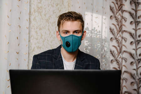 Man wear medical mask work with laptop. Avoid contact with other people. Stay home. Working from home. Online.の写真素材