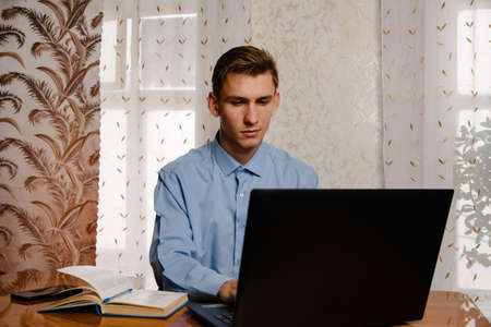 A male freelancer works online on a laptop at home at a Desk.Businessman using laptop at home. Internet marketing, freelance work, working from home, online learning, studying concept.の写真素材