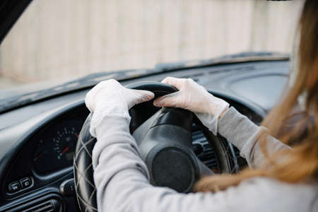 Female driver in a mask and gloves holding the steering wheel, close-up.Prevention of coronavirus infection.Protective measures against coronavirus, covid-19の写真素材