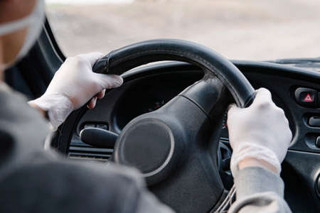 Male driver in a mask and gloves holding the steering wheel, close-up.Prevention of coronavirus infection.Protective measures against coronavirus, covid-19の写真素材