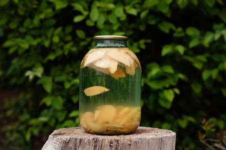 Canned quince fruit compote in a glass jar.Canned fruit compote against the background of nature.Organic homegrown produceの写真素材