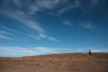Runner athlete running in desert. Fit man training cardio outdoors. Summer sport fitness run in...