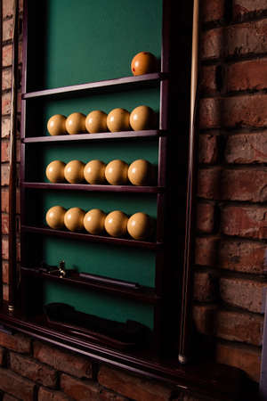 Yellow billiard balls and cue ball for billiards on the shelf,close up.Green cloth. Wooden cueの写真素材