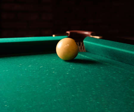 Yellow billiard ball on green billiard table close up.Billiard ball near the pocket