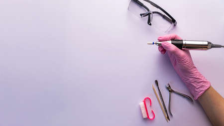 Nail drill. A manicurist in gloves holds a nail drill on white bacgroundの写真素材