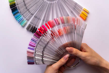 Woman hands holding manicure nail color samples palette on white background with copy space, top viewの写真素材