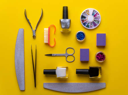 manicure and pedicure tools and accessories on yellow background top view.multicolored flat lay compositionの写真素材