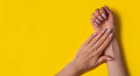 Female hands with a beautiful manicure on a yellow background,top view,flat lay. Manicure concept,bannerの写真素材