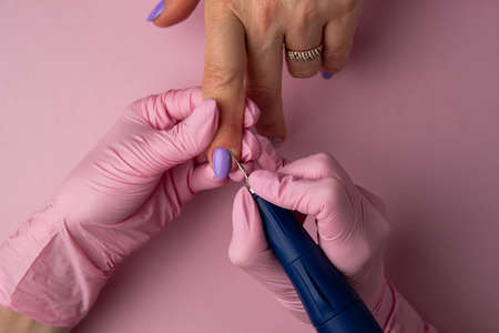 Manicure process, top view.Manicure in beauty salon.Manicure concept, flat lay. Woman use electric nail file drill in beauty salon. nails manicure process or operation in close upの写真素材