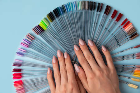 Woman hands and manicure nail color samples palette on blue background with copy space, top viewの写真素材
