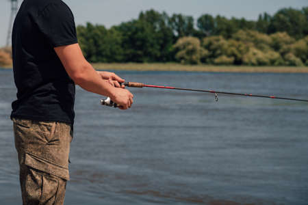 Fishing in river.Portrait of a fisherman with a fishing rod.A fisherman with a fishing rod on the river bank. Man fisherman catches a fish.の写真素材