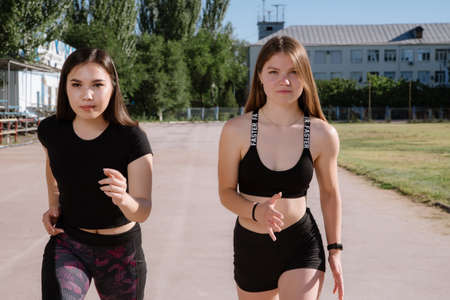 Two athletes at the starting position in the stadium. Athletic girls run in the stadium.Girls are doing exercises, stretching. Sport and healthy lifestyle.の写真素材