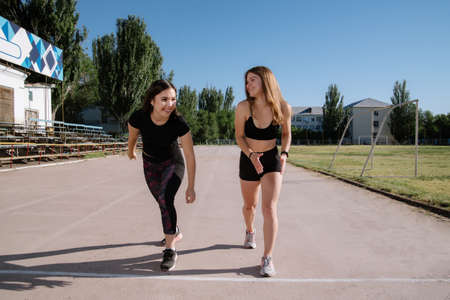 Two athletes at the starting position in the stadium. Athletic girls run in the stadium.Girls are doing exercises, stretching. Sport and healthy lifestyle.の写真素材