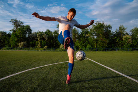 Young male soccer player juggles a ball on a soccer field.Athlete juggling the football with his feet in stadium.Football sports conceptの写真素材