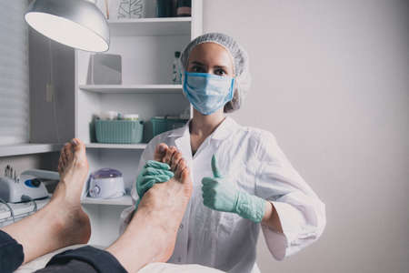 Young woman getting professional pedicure in beauty salon. Pedicure master paints toenails with gel polish. Master during a pedicure. The process of professional pedicures.の写真素材