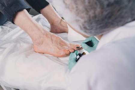 Young woman getting professional pedicure in beauty salon.Pedicure master paints toenails with gel polish.Master during a pedicure. The process of professional pedicures.の写真素材