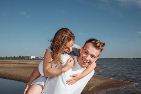 Couple in love on the beach.Portrait of a couple in love on the beach. A young girl hugs a guy.Couple Love Beach Romance Togetherness Concept.の写真素材