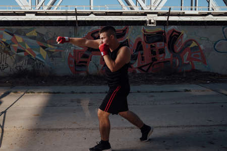 A man in red boxing bandages strikes. Male boxer during training.Sports and boxing conceptの写真素材