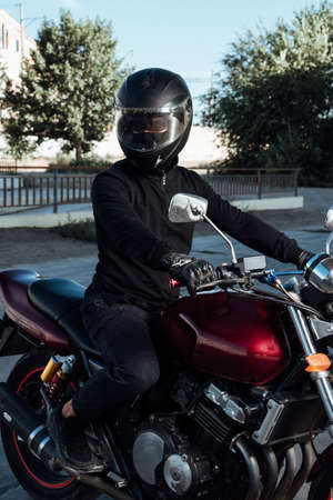 Man seat on the motorcycle.Man in helmet posing on motorcycle.Motorcyclist in black helmet on a red bikeの写真素材