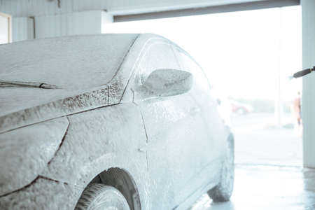 Car wash with soap. Washing car with soap. Close up concept.Shot of a man washing his car under high pressure water outdoors.の写真素材