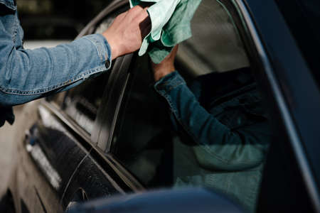Car detailing - man holds the microfiber in hand and polishes the car. Selective focus.male hand...