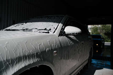 Car wash with soap.Car getting a wash with soap, car washing.Soaping with foam on car in...