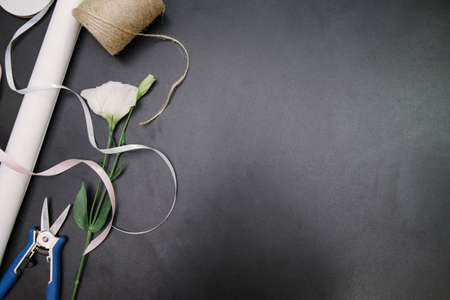 Florist equipment with flowers on wooden background, top view. Florist workplace: flowers and...