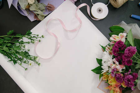 Florist equipment with flowers on wooden background, top view. Florist workplace: flowers and accessoriesの写真素材