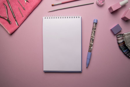 Top view of open empty spiral notebook with pen and manicure accessories on pink background, flat layの写真素材