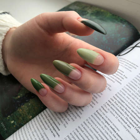 Green manicure. Hands of a woman with green manicure on nails.Manicure beauty salon concept. Empty place for text or logo.のeditorial素材
