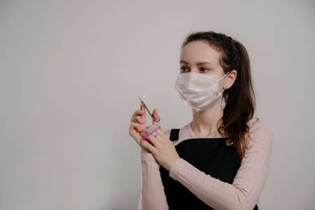 Manicure tools in hands of female manicurist wearing mask. woman brunette manicurist on gray backgroundの写真素材