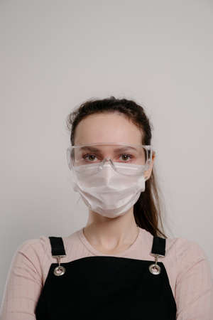 Woman in goggles and a medical mask.Portrait of a young woman, a brunette with collected hair in goggles and a protective medical mask.Looks straight,の写真素材