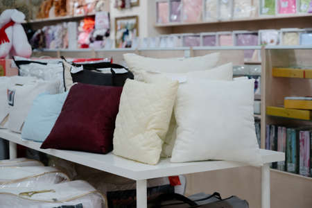 A row of colorful pillows on a shelf in a textile store.Many colorful pillows are sold in the...