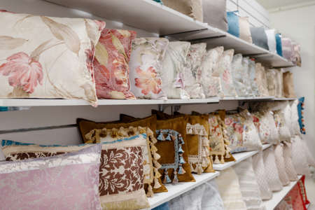A row of colorful pillows on a shelf in a textile store.Many colorful pillows are sold in the...