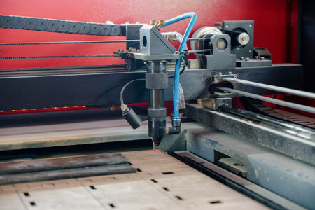 Laser cutting beam over plywood sheet.Laser engraver working and engraving flat wooden board