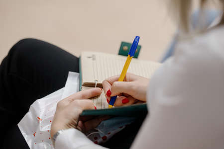 A woman's writing hand.A woman writes in a notebook close-up.A woman's hand writes with a ballpoint pen close-upの写真素材