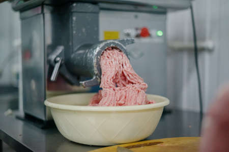Close up of front part of meat grinder or mincing-machine with mincemeat in. Showing the forcemeat...