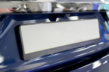 Close-up view of a car's license plate holder, featuring a white background. Rear view of new car with blank numberの写真素材