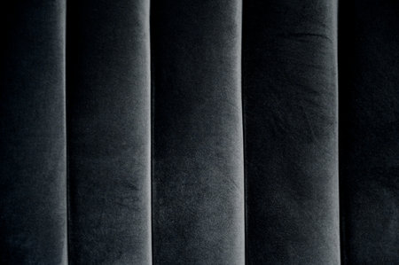 texture of dark gray fabric with vertical folds. Detail of a sofa with grey upholstery