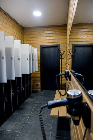 Modern changing room interior with wood trim and lockers. Changing room with lockers, mirrors and hair dryersの写真素材