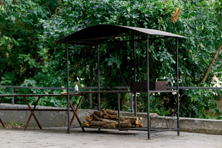 Barbecue area. Metal structure with barbecue and woodpile. Outdoor BBQ