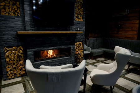 Cozy living room with a modern stone fireplace, warm flames flickering inside. fireplace with burning woodの写真素材