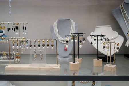 Elegant showcase with earrings and pearl necklaces on bust mannequins in the store.Close-up: Baroque...