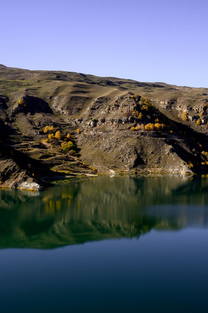 Panorama of autumn mountains with terracotta slopes and a clear lake. A mountain landscape with a...