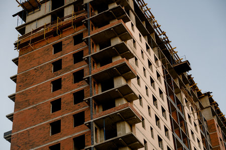 A multi-story residential building under construction made of red brick and concrete. Unfinished...