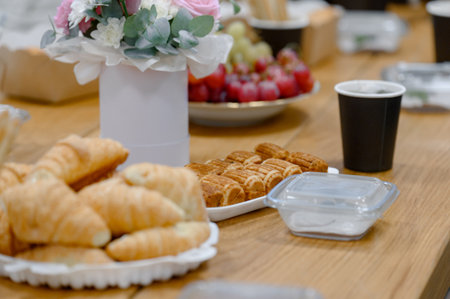 Catering for an event with croissants, rolls, coffee and flowers. A light breakfast or snack at a business meeting with aromatic pastries and drinks.の写真素材